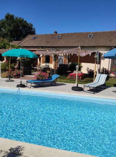 - une piscine avec 2 chaises longues et des parasols dans l'établissement Chambre d'hôtes à mouleydier, à Mouleydier