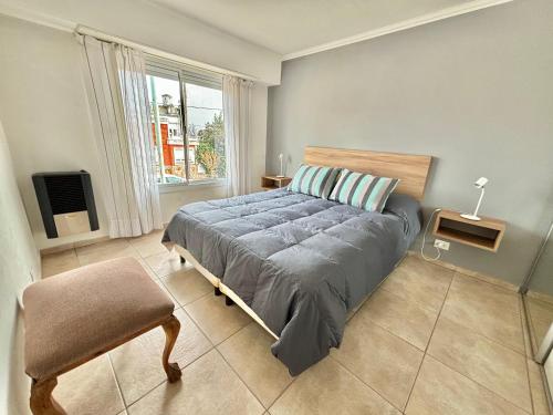 Un dormitorio con una cama y una silla y un televisor. en Departamentos del Parque 2º, en Olavarría