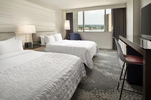 a hotel room with two beds and a desk at Le Meridien New Orleans in New Orleans