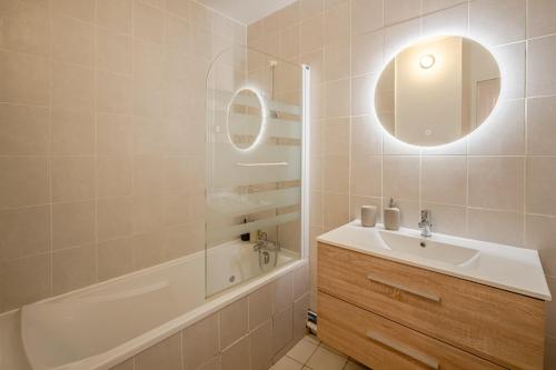 une salle de bain avec un lavabo, une baignoire et un miroir dans l'établissement OIQIA • Olympe, à Narbonne