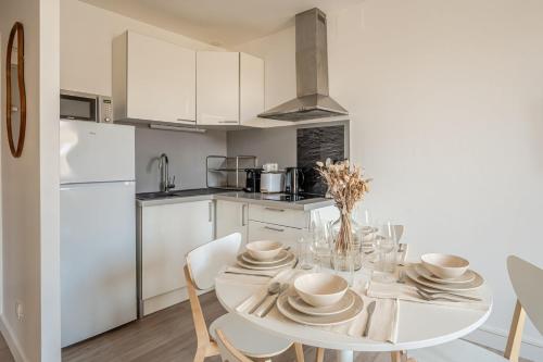 une cuisine blanche avec une table et des chaises blanches dans l'établissement OIQIA • Olympe, à Narbonne