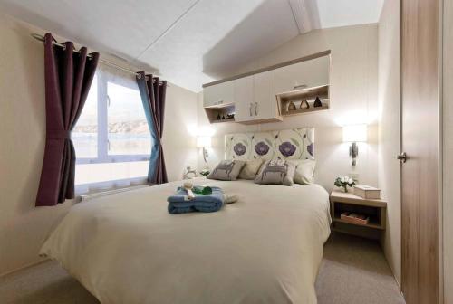 a bedroom with a large white bed with a window at Lagooncombe modern and cosy holiday home in Haverigg
