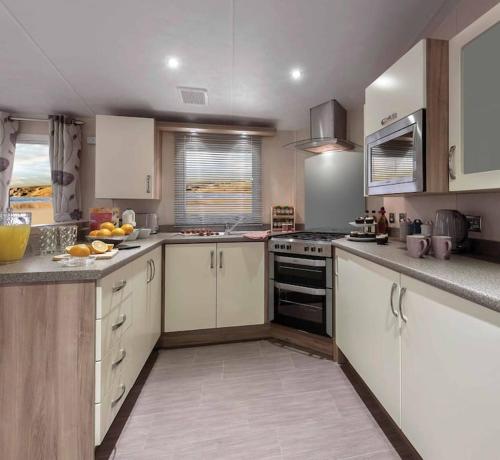 a kitchen with white cabinets and a stove top oven at Lagooncombe modern and cosy holiday home in Haverigg