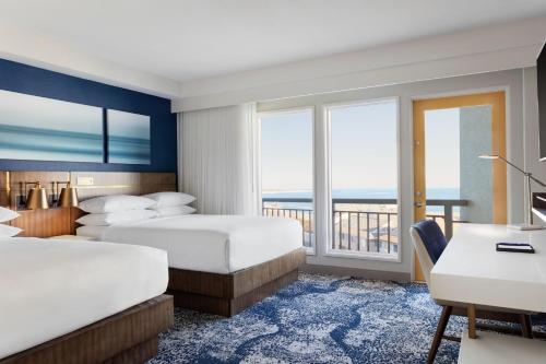 a hotel room with two beds and a desk at Delta Hotels by Marriott™ Virginia Beach Waterfront Suites in Virginia Beach