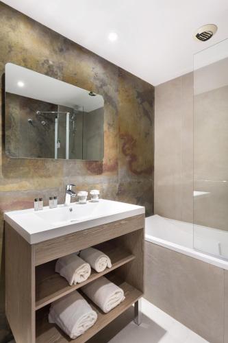 a bathroom with a sink and a mirror and a tub at Hôtel Birdy by Happyculture in Aix-en-Provence