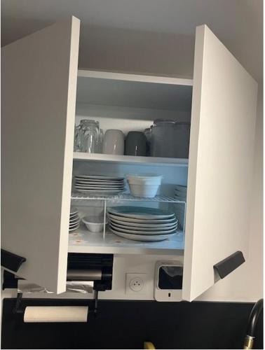 une armoire blanche avec des assiettes et de la vaisselle dans l'établissement Studio Colonel MOLL, à Vaires-sur-Marne