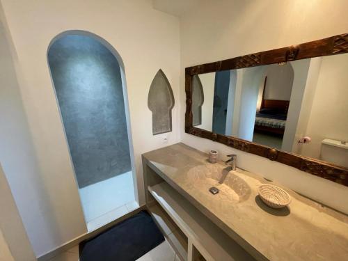 a bathroom with a sink and a large mirror at Agence Adjana Resort - Résidence du Port 3 in Sali Tapé