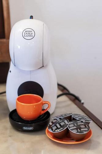 a coffee maker with an orange cup and three remote controls at Cozy chalet "Da Silvio e Bruna" in Santo Stefano di Sessanio