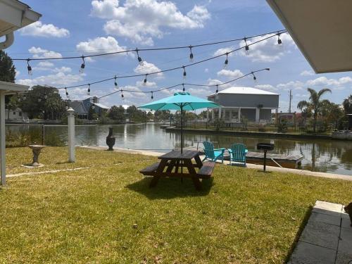 a picnic table with an umbrella next to a river at Cabin by the Sea - Waterfront Direct Gulf Access- Pontoon Boat Rental On Site or Bring Your Boat- Paddlecraft included in Hernando Beach