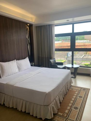 a large bed in a hotel room with a large window at Agulu Lake Resort and Conference Centre in Ekwulobia
