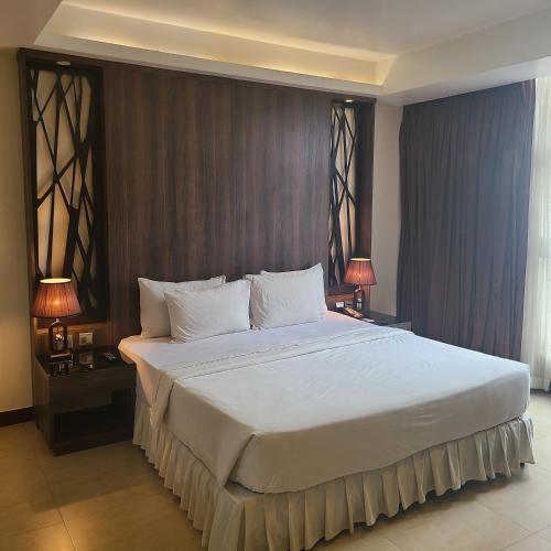 a bedroom with a large white bed with two lamps at Agulu Lake Resort and Conference Centre in Ekwulobia