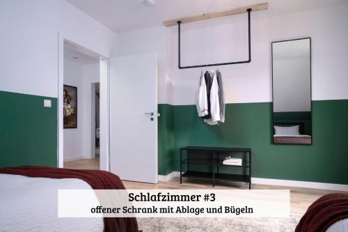a bedroom with green and white walls and a mirror at LenHaus Sundern - Ferienhaus mit Kamin & Garten in Sundern