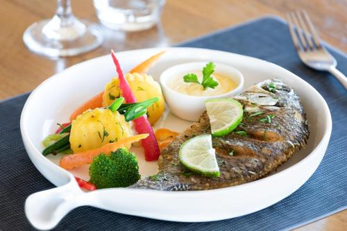 a plate of food with fish and vegetables on a table at Four Points by Sheraton Dar es Salaam New Africa in Dar es Salaam