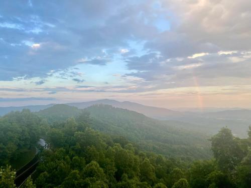 a rainbow in the sky over a valley with trees at Skyline Village Inn in Spruce Pine