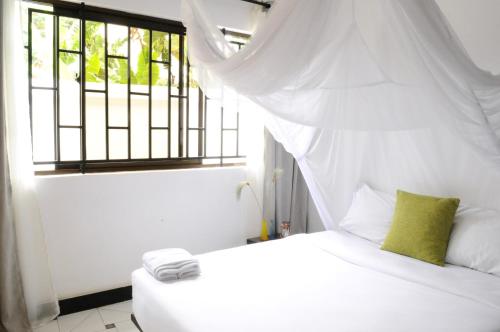 a bedroom with a white bed with a window at OYA Guest House in Usa River