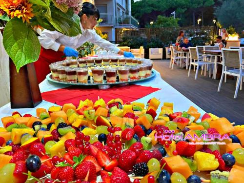 a woman standing next to a table full of fruit at HOTEL AMBRA - Fronte Mare - Vicinissimi al Centro in Milano Marittima