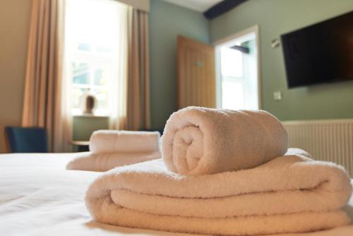 a stack of towels sitting on top of a bed at The Angel Inn Hotel in Pershore