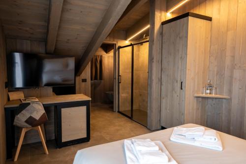 a bedroom with a bed and a tv and a bathroom at Le Suites de San Campel RTA in Ponte di Legno