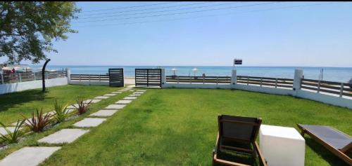 a lawn with a bench and the ocean in the background at Thea Suites in Nea Kalikratia