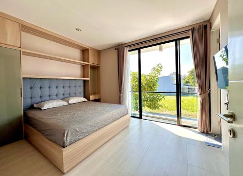 a bedroom with a bed and a large window at Charming 4BR House in Northwest Park, West Surabaya by Le Ciel Hospitality in Surabaya