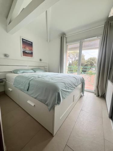 un lit dans une chambre avec une grande fenêtre dans l'établissement Duplex T3 Boulouris Pieds dans l eau, à Saint-Raphaël
