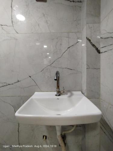 a white sink in a bathroom with marble walls at junagadh places in Ujjain