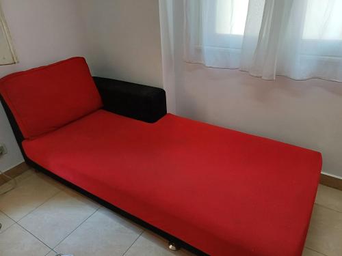 a red couch in a room with a window at A room in an apartment in Nasr City, Cairo, near Azhar university , 15 minutes from Cairo Airport,غرفة بشقة بمدينة نصر بالقاهرة بالحي الثامن 15 دقيقة من مطار القاهرة و 7 دقيقة من معهد الفجر و 12 دقيقة لمعهد ابانة لتعليم اللغة العربية و 26 دقيقة لوسط البلد in Cairo