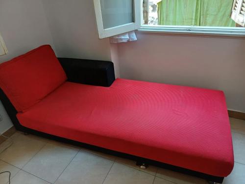 a red couch in a room with a window at A room in an apartment in Nasr City, Cairo, near Azhar university , 15 minutes from Cairo Airport,غرفة بشقة بمدينة نصر بالقاهرة بالحي الثامن 15 دقيقة من مطار القاهرة و 7 دقيقة من معهد الفجر و 12 دقيقة لمعهد ابانة لتعليم اللغة العربية و 26 دقيقة لوسط البلد in Cairo