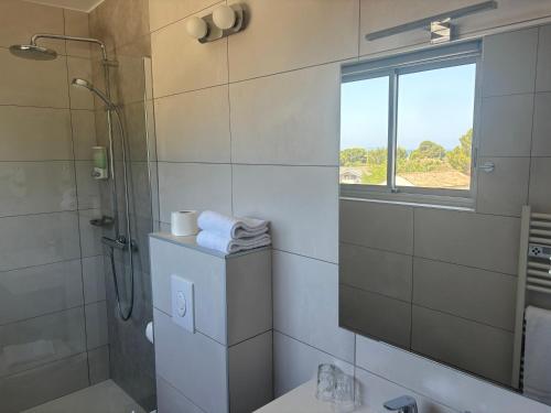 a bathroom with a shower and a toilet and a window at Hotel La Voile in Bormes-les-Mimosas