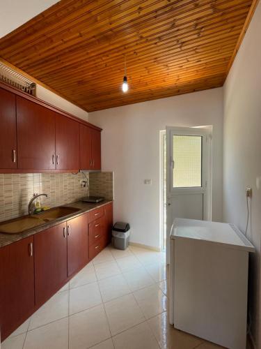 a kitchen with brown cabinets and a wooden ceiling at Vila Gusti in Borsh