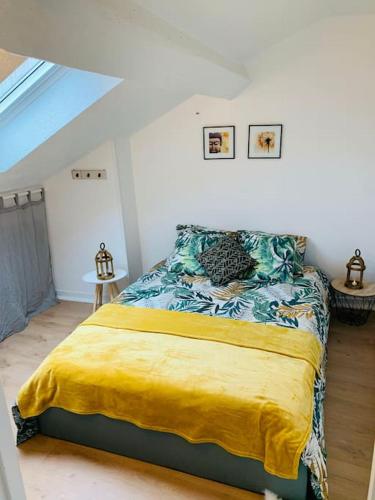 une chambre avec un lit avec une couverture jaune dans l'établissement Appartement en centre-ville, à Remiremont
