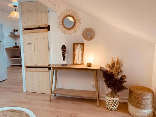 Cette chambre comprend une table et un miroir mural. dans l'établissement Appartement en centre-ville, à Remiremont