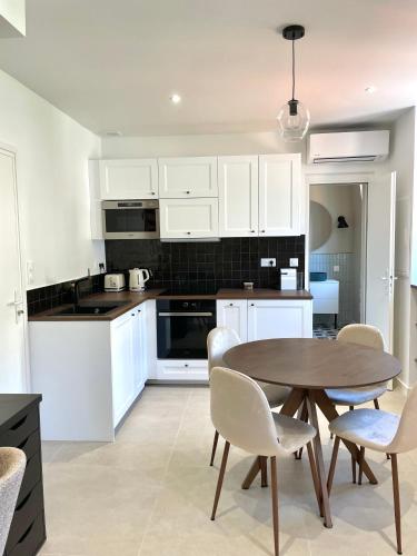 une cuisine avec des armoires blanches et une table et des chaises dans l'établissement Studio de charme proche gare, à Menton
