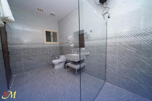 a bathroom with a toilet and a glass shower at شقق اس ام للشقق الفندقية in Hafr Al Baten