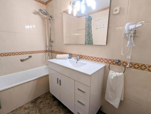 Un baño con lavabo, bañera y espejo. en Spacious apartment in Cabrera de Mar with sea view, en Cabrera de Mar