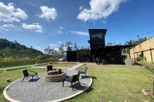 a patio with chairs and a fire pit in a yard at The Black & White Box Villa - Genting Highland Foot Area in Bentong