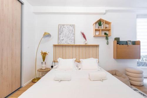 - une chambre avec un grand lit blanc et des oreillers blancs dans l'établissement GuestReady - Stylish Retreat near République for 2, à Paris