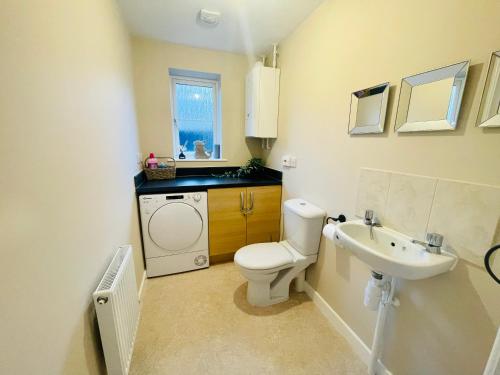 a bathroom with a toilet and a sink at Spacious 4 Bedroom, 3 Bath House by Jesswood Properties Contractors, Business and Leisure with Free Parking and WIFI in Peterborough