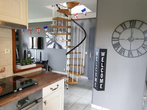 a kitchen with a clock and a spiral staircase at Duplex les pieds dans l'eau in Grandcamp-Maisy