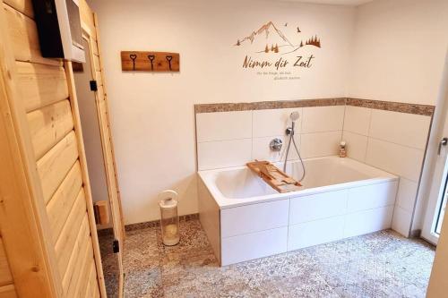 a bathroom with a tub and a sign on the wall at Time Out Moments Haus mit eigener Sauna in Grafenau