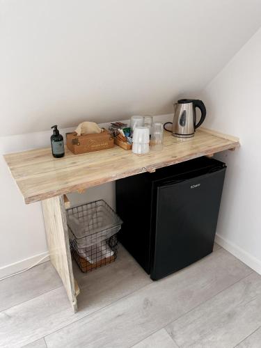 a wooden table with a microwave on top of a refrigerator at Kirsebærkroen - The Inn Between in Præstø