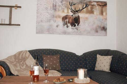 a living room with a couch and a table with wine glasses at Time Out Moments Haus mit eigener Sauna in Grafenau