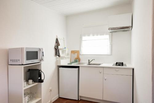 a white kitchen with a microwave and a sink at Além Monte Retreat, Peaceful Hideaway on the Alentejo Coast in Colos