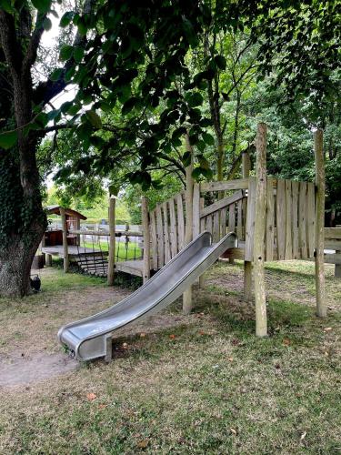 a slide in a park next to a wooden fence at Kirsebærkroen - The Inn Between in Præstø