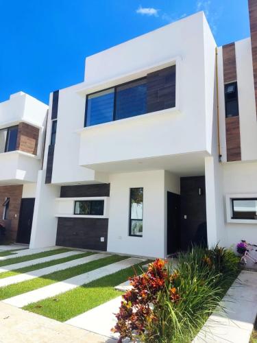 a white house with black doors and flowers at Casa entera de lujo Playa del Carmen in Playa del Carmen