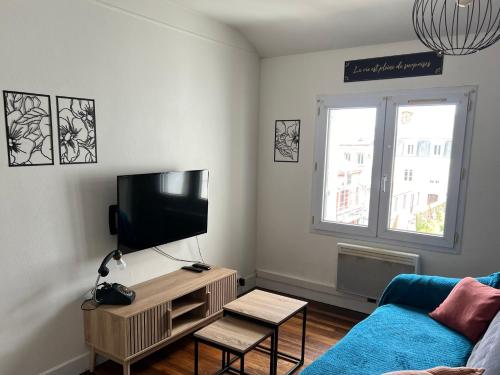 un salon avec un canapé bleu et une télévision à écran plat dans l'établissement Appartement douillet, à Cherbourg en Cotentin