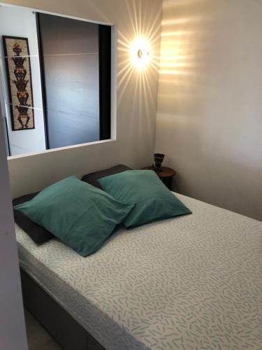 une chambre avec un lit avec deux oreillers verts dans l'établissement Coquet studio avec grande terrasse, à Antibes