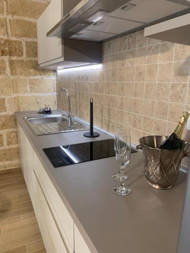 a kitchen with a sink and a counter with wine glasses at Le Dimore del Castello in Nardò