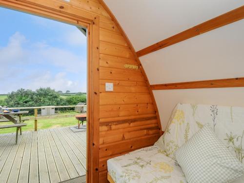a room with a couch on a wooden deck at Fox Den Penbugle Organic Farm in Liskeard