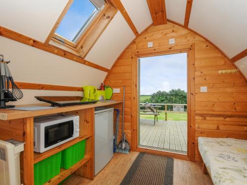 a kitchen in a tiny house with a large window at Fox Den Penbugle Organic Farm in Liskeard